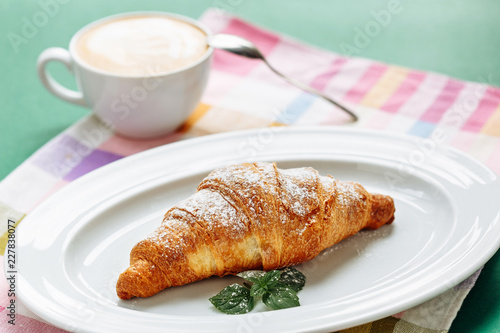 Croissant with coffee cappuccino for breakfast. Side view on cloth napkin background