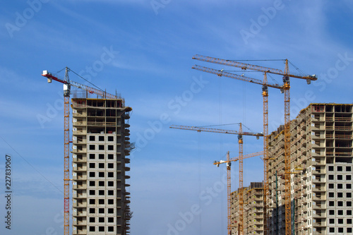 Image of construction of new residential buildings with a variety of construction cranes.