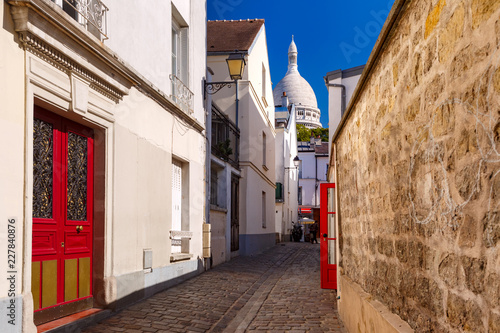 Fototapeta Naklejka Na Ścianę i Meble -  Cozy old street and Sacre-Coeur Basilica at the sunny summer morning, quarter Montmartre in Paris, France