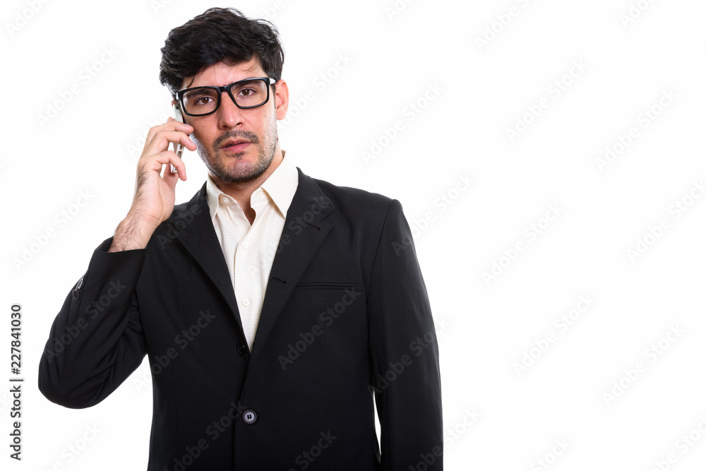 Studio shot of young Persian businessman talking on mobile phone Studio shot of young Persian businessman talking on mobile phone