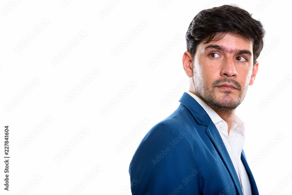 Studio shot of young Persian businessman thinking while looking Studio shot of young Persian businessman thinking while looking