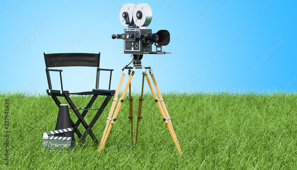 Obraz premium Cinema concept. Movie camera with film reels, chair, megaphone and clapperboard on the green grass against blue sky, 3D rendering