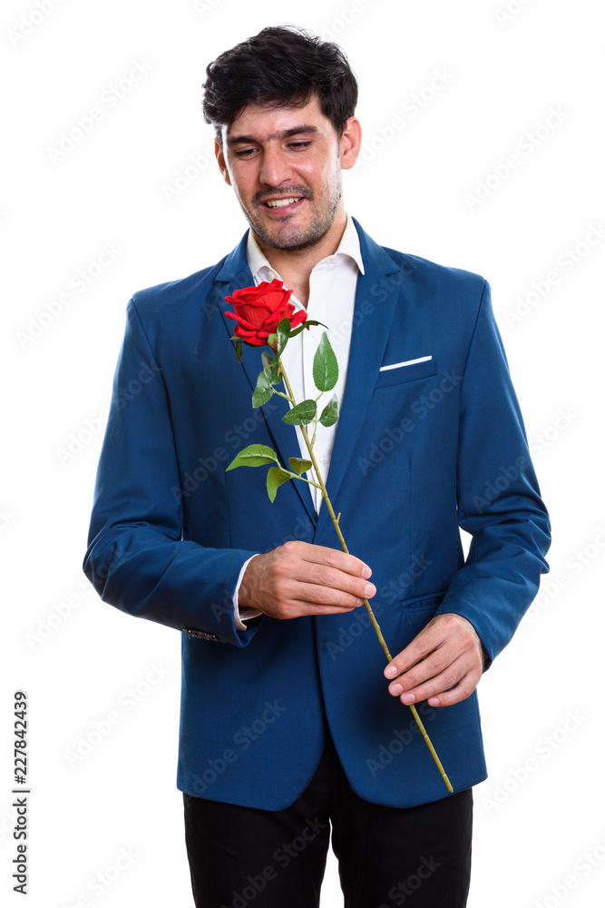 Studio shot of young happy Persian businessman smiling while hol Studio shot of young happy Persian businessman smiling while hol