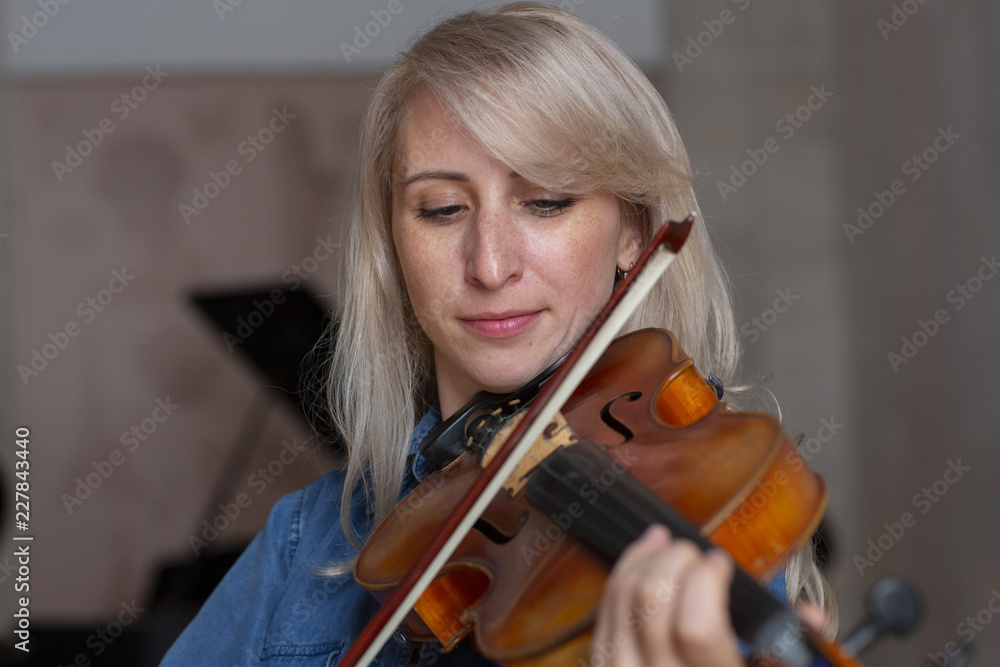 Young beautiful woman violin player looking at camera over instrument on her shoulder holding bow. Young beautiful woman violin player looking at camera over instrument on her shoulder holding bow.