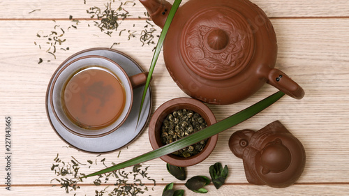 Зеленый чай в керамической чашке и чайнике, фигурка будды