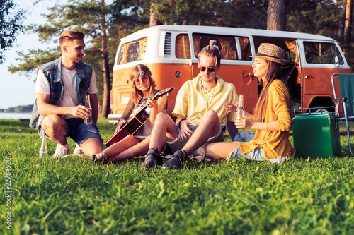 Hipster friends by camper van at festival on a summers day. © opolja