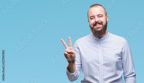Young caucasian hipster man over isolated background smiling with happy face winking at the camera doing victory sign. Number two.