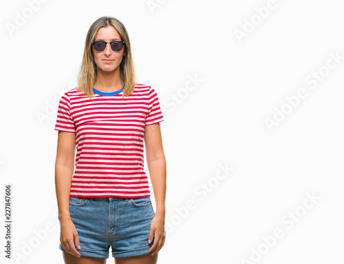 Young beautiful woman wearing sunglasses over isolated background with serious expression on face. Simple and natural looking at the camera.