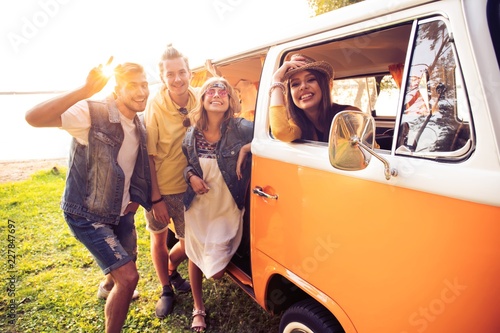 summer holidays, road trip, vacation, travel and people concept - smiling young hippie friends having fun over minivan car. photo