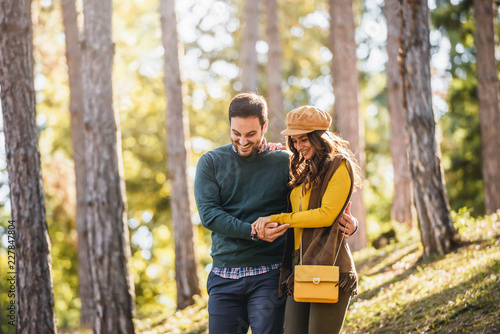 Beautiful smiling love couple walking in colorful autumn forest park