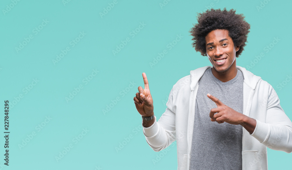 Afro american man wearing sweatshirt over isolated background smiling and looking at the camera pointing with two hands and fingers to the side. Afro american man wearing sweatshirt over isolated background smiling and looking at the camera pointing with two hands and fingers to the side.