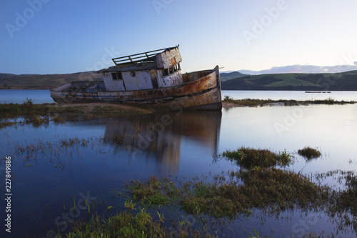 Fényképezés Old boat shipwrecked in the murky waters