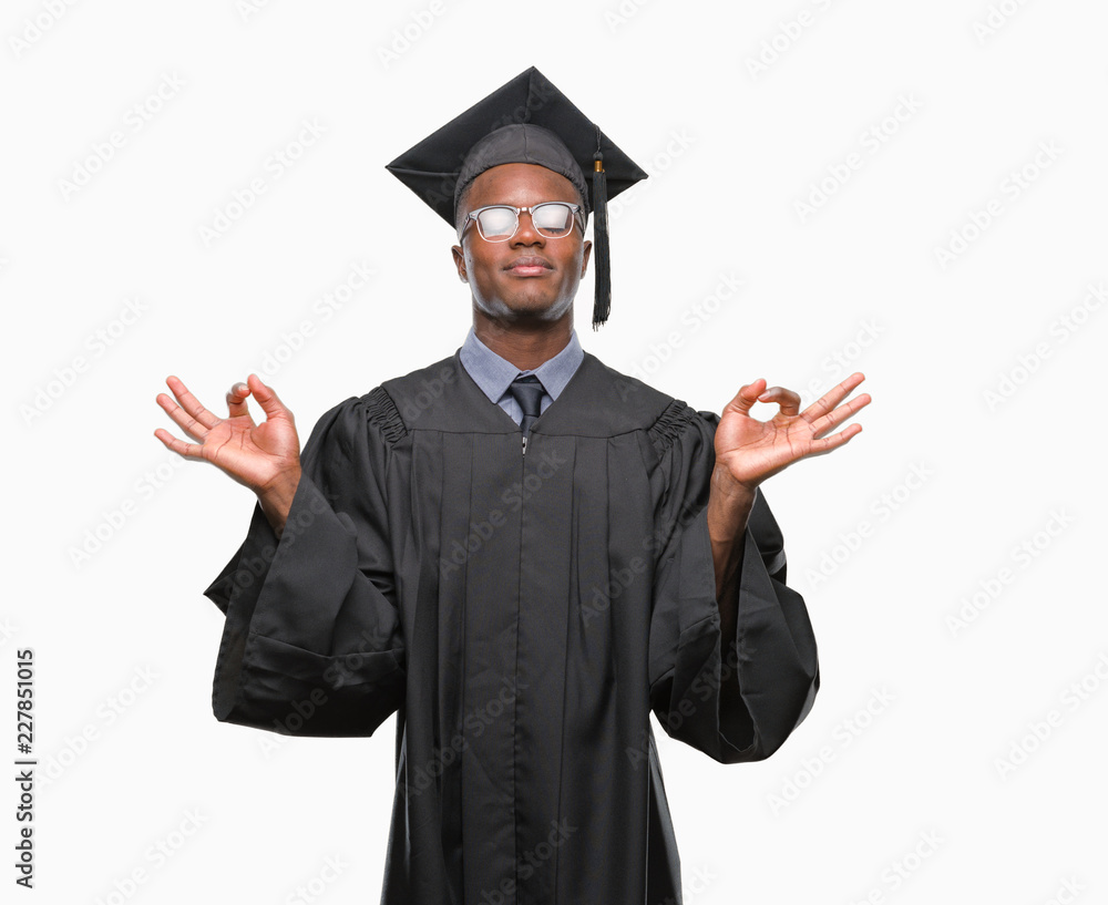 Young graduated african american man over isolated background relax and smiling with eyes closed doing meditation gesture with fingers. Yoga concept. Young graduated african american man over isolated background relax and smiling with eyes closed doing meditation gesture with fingers. Yoga concept.