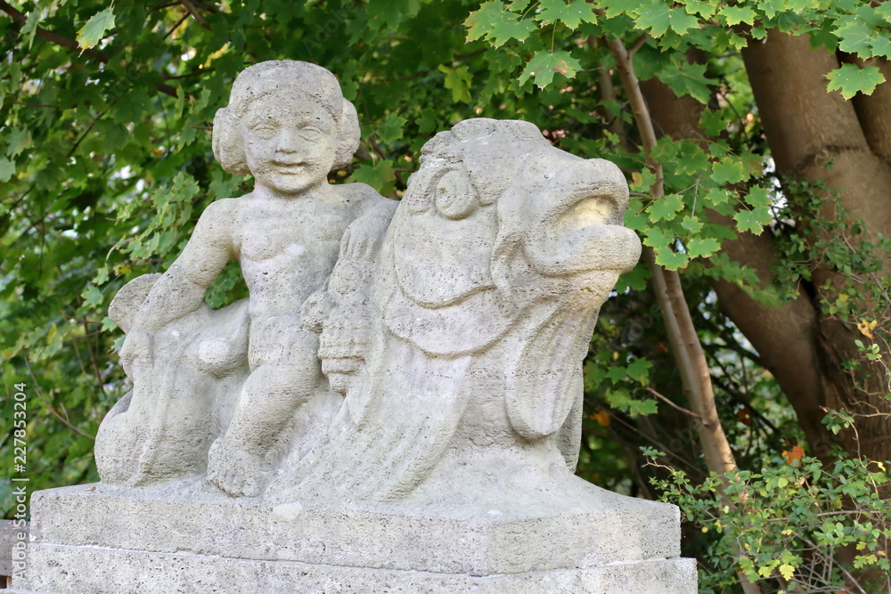Stone figure, weathered, child on fish, detail, bridge town Hamm in Germany