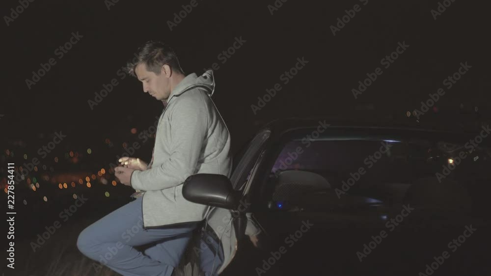 male driver on the background of the night city uses a smartphone male driver on the background of the night city uses a smartphone