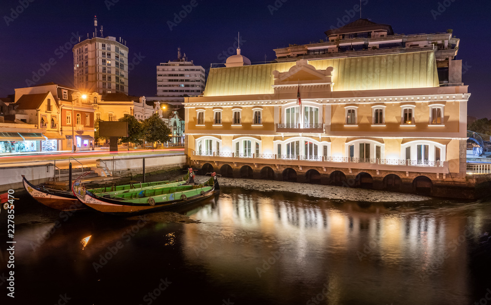 View of the central canal in Aveiro at night with moliceiros moored and building illuminated. City center of Aveiro in Portugal.