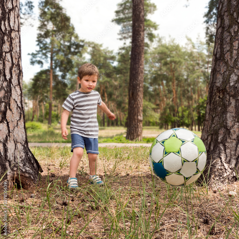 Boy kicking the ball on the play yard. Kid plays with ball in the park. Having fun outdoor. Leisure activities. Happy childhood. Healthy children concept. Outdoor activities. Boy kicking the ball on the play yard. Kid plays with ball in the park. Having fun outdoor. Leisure activities. Happy childhood. Healthy children concept. Outdoor activities.
