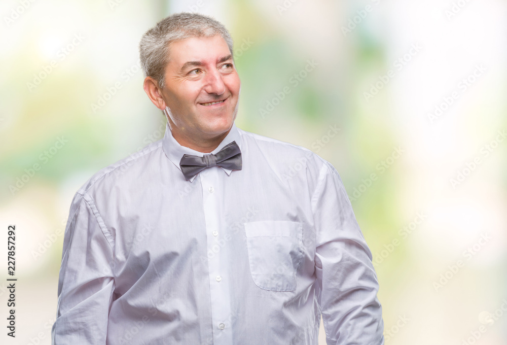 Handsome senior man wearing bow tie over isolated background looking away to side with smile on face, natural expression. Laughing confident. Handsome senior man wearing bow tie over isolated background looking away to side with smile on face, natural expression. Laughing confident.