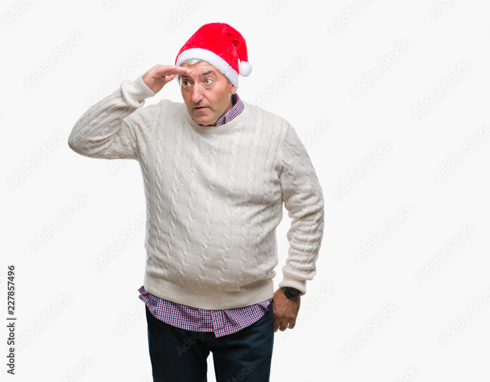 Handsome senior man wearing christmas hat over isolated background very happy and smiling looking far away with hand over head. Searching concept. Handsome senior man wearing christmas hat over isolated background very happy and smiling looking far away with hand over head. Searching concept.