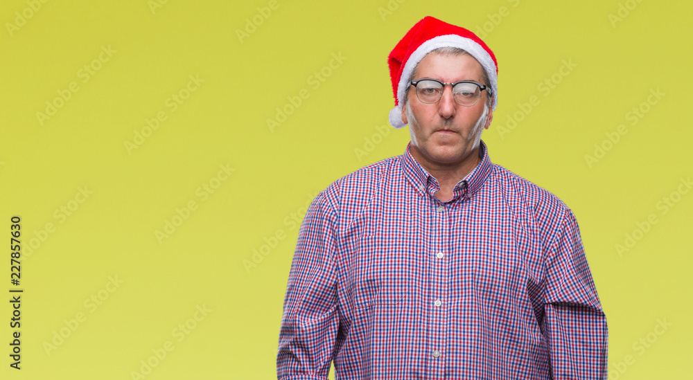 Handsome senior man wearing christmas hat over isolated background with serious expression on face. Simple and natural looking at the camera. Handsome senior man wearing christmas hat over isolated background with serious expression on face. Simple and natural looking at the camera.