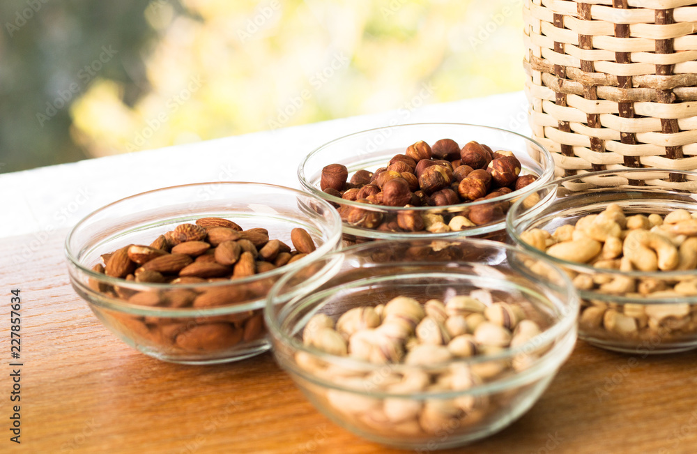 Assortment of mixed nuts and wicker basket on wood table background Assortment of mixed nuts and wicker basket on wood table background