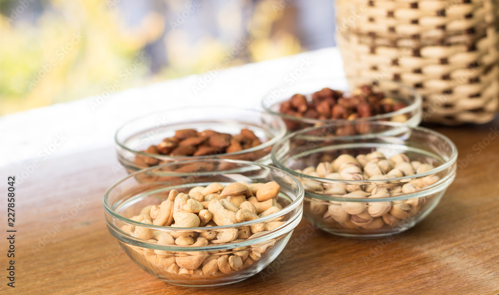 Assortment of mixed nuts and wicker basket on wood table background Assortment of mixed nuts and wicker basket on wood table background