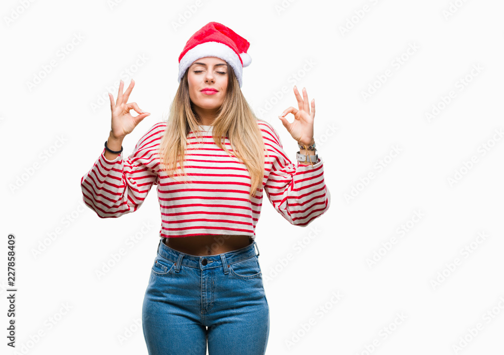 Young beautiful woman wearing christmas hat over isolated background relax and smiling with eyes closed doing meditation gesture with fingers. Yoga concept. Young beautiful woman wearing christmas hat over isolated background relax and smiling with eyes closed doing meditation gesture with fingers. Yoga concept.