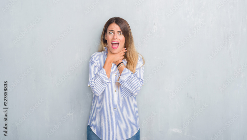 Young adult woman over grey grunge wall wearing fashion business outfit shouting and suffocate because painful strangle. Health problem. Asphyxiate and suicide concept. Young adult woman over grey grunge wall wearing fashion business outfit shouting and suffocate because painful strangle. Health problem. Asphyxiate and suicide concept.