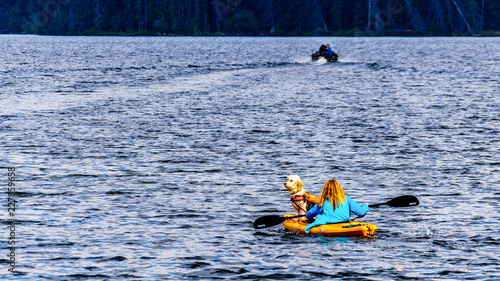 Dog sitting on the front of a Kayak steered by a woman on Lac Le Jeune lake near Kamloops, British Columbia, Canada

