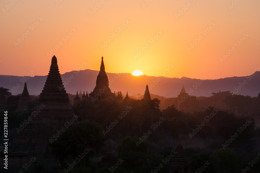 Silhouettes of Burmese Pagodas while sun is setting in the mountains from the view of Shwesandaw Pagoda, Bagan, Myanmar