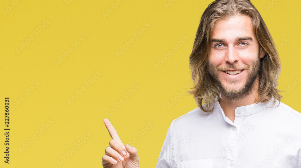 Young handsome man with long hair over isolated background with a big smile on face, pointing with hand and finger to the side looking at the camera. Young handsome man with long hair over isolated background with a big smile on face, pointing with hand and finger to the side looking at the camera.