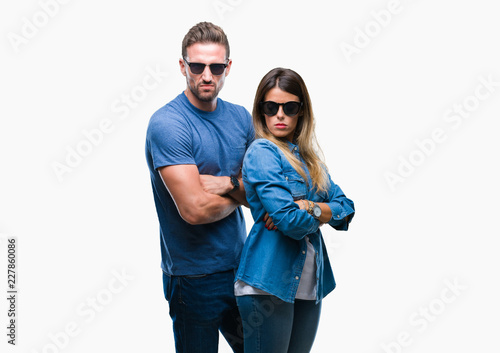 Young couple in love wearing sunglasses over isolated background skeptic and nervous, disapproving expression on face with crossed arms. Negative person.