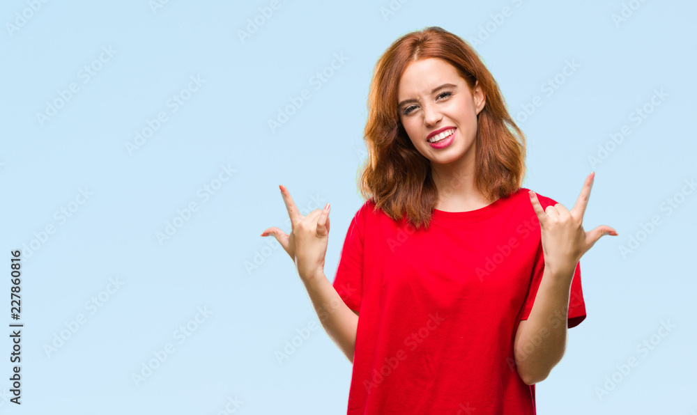 Young beautiful woman over isolated background shouting with crazy expression doing rock symbol with hands up. Music star. Heavy concept. Young beautiful woman over isolated background shouting with crazy expression doing rock symbol with hands up. Music star. Heavy concept.