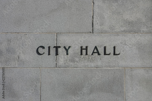 Fotografie Metal letters reading CITY HALL are shown affixed to a concrete exterior wall of a municipal building