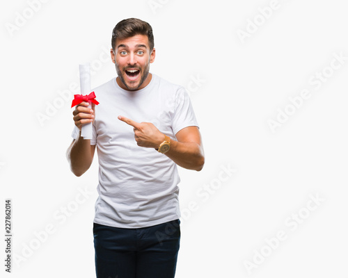 Young handsome man holding degree over isolated background very happy pointing with hand and finger