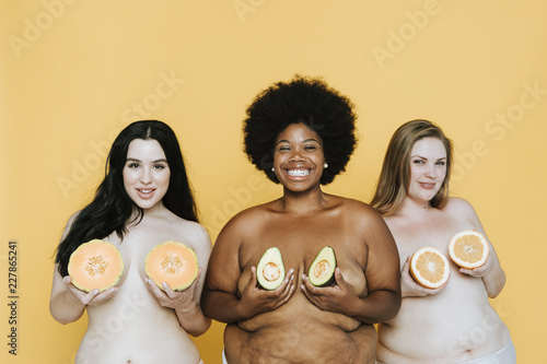 Diverse curvy nude women holding fruits over their breasts photo