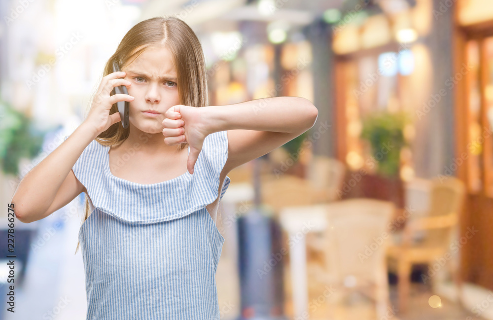 Young beautiful girl talking on the phone over isolated background with angry face, negative sign showing dislike with thumbs down, rejection concept