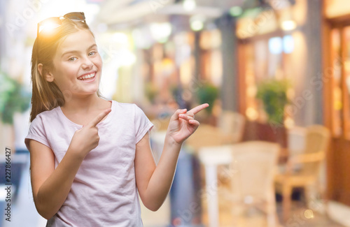 Young beautiful girl wearing sunglasses over isolated background smiling and looking at the camera pointing with two hands and fingers to the side.