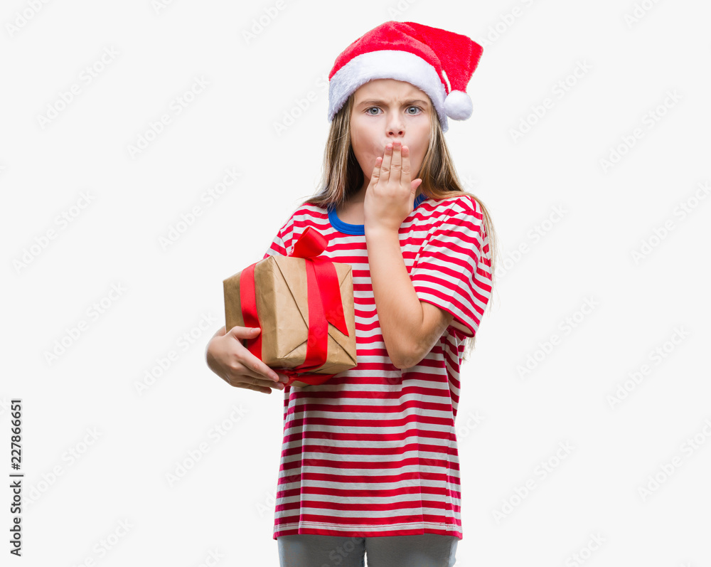Young beautiful girl wearing christmas hat and holding gift over isolated background cover mouth with hand shocked with shame for mistake, expression of fear, scared in silence, secret concept Young beautiful girl wearing christmas hat and holding gift over isolated background cover mouth with hand shocked with shame for mistake, expression of fear, scared in silence, secret concept