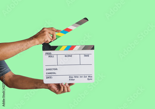 Hand holding a film clapboard slate or movie slate isolated on green background, with clipping path.