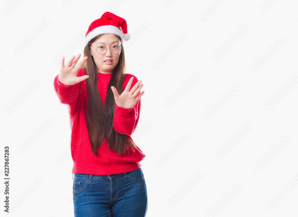 Young Chinese woman over isolated background wearing christmas hat afraid and terrified with fear expression stop gesture with hands, shouting in shock. Panic concept. Young Chinese woman over isolated background wearing christmas hat afraid and terrified with fear expression stop gesture with hands, shouting in shock. Panic concept.