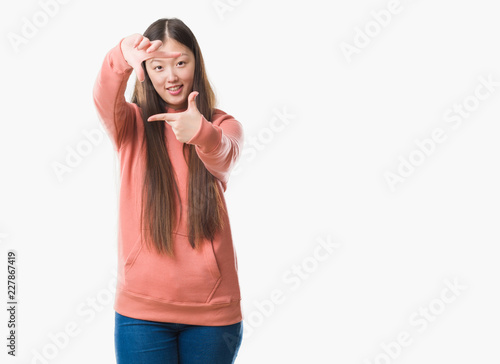 Young Chinese woman over isolated background wearing sport sweathshirt smiling making frame with hands and fingers with happy face. Creativity and photography concept.