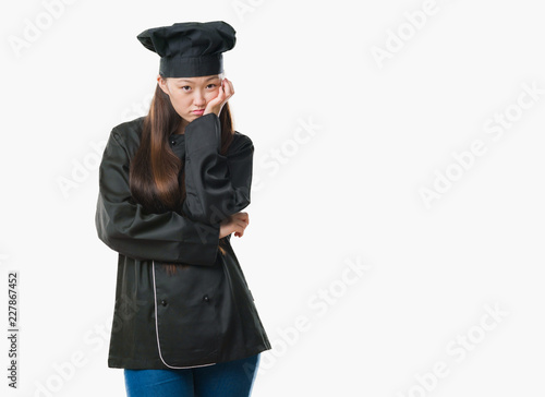 Young Chinese woman over isolated background wearing chef uniform thinking looking tired and bored with depression problems with crossed arms.