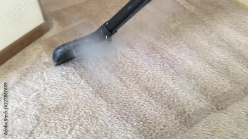 Carpet cleaning professional works wand from above while hot steamy water drives down into surface before extraction thereafter.  