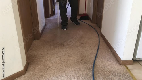 Carpet cleaning professional sprays chemicals onto carpeting to prepare for vacuuming surface thereafter.  