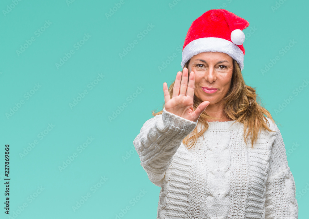 Middle age senior hispanic woman wearing christmas hat over isolated background doing stop sing with palm of the hand. Warning expression with negative and serious gesture on the face. Middle age senior hispanic woman wearing christmas hat over isolated background doing stop sing with palm of the hand. Warning expression with negative and serious gesture on the face.