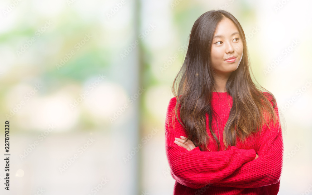 Young asian woman wearing winter sweater over isolated background smiling looking side and staring away thinking. Young asian woman wearing winter sweater over isolated background smiling looking side and staring away thinking.