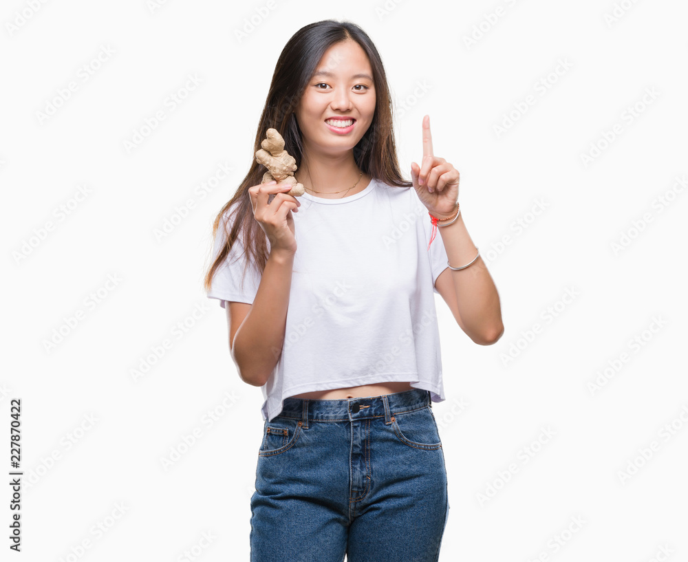 Young asian woman holding fresh organic over isolated background surprised with an idea or question pointing finger with happy face, number one Young asian woman holding fresh organic over isolated background surprised with an idea or question pointing finger with happy face, number one
