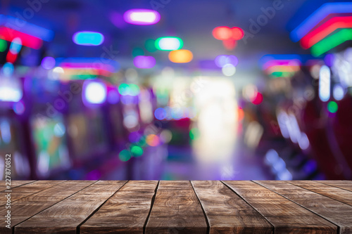 Empty wood table top on abstract blurred game center shop and nightclub lights background - can be used for display or montage your products