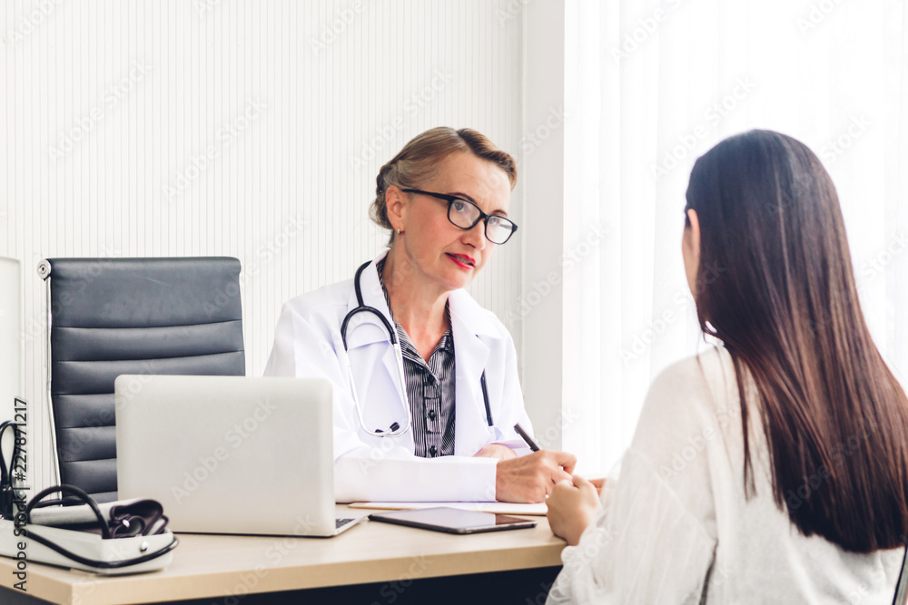 Doctor discussing and consulting with female patien on doctors table in hospital.healthcare and medicine Doctor discussing and consulting with female patien on doctors table in hospital.healthcare and medicine